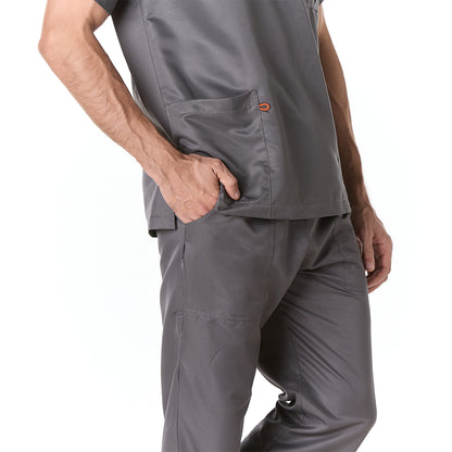 Hombre vistiendo pijama sanitario color gris oscuro con cuello en v y pantalon recto - perfil