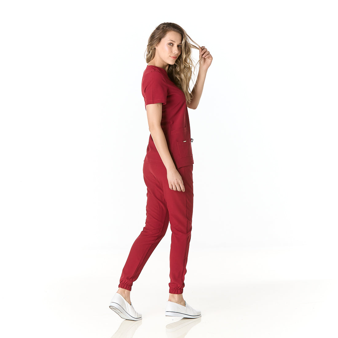 Mujer vistiendo pijama sanitario color vino con cuello en v y pantalon tipo jogger - perfil