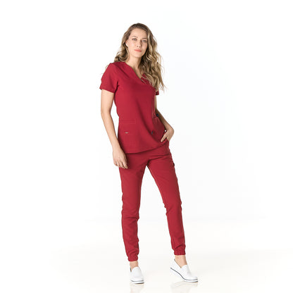 Mujer vistiendo pijama sanitario color vino con cuello en v y pantalon tipo jogger